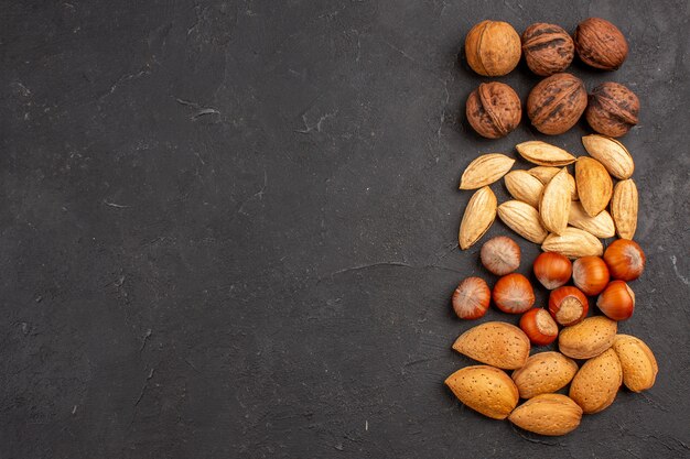 Top view of different fresh nuts on dark surface