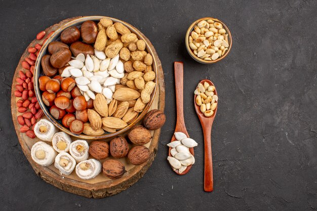 Top view of different fresh nuts on dark surface