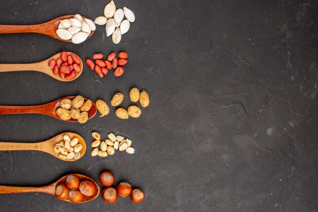 Top view of different fresh nuts peanuts and other nuts on dark surface