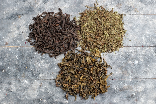 Top view different fresh tea dried on grey desk