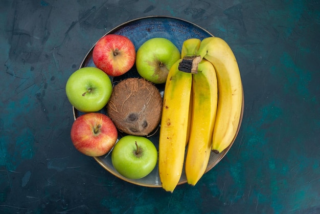 Top view different fruit composition coconut apples and bananas on dark-blue desk