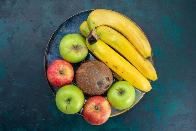 Top view different fruit composition coconut apples and bananas on dark-blue desk
