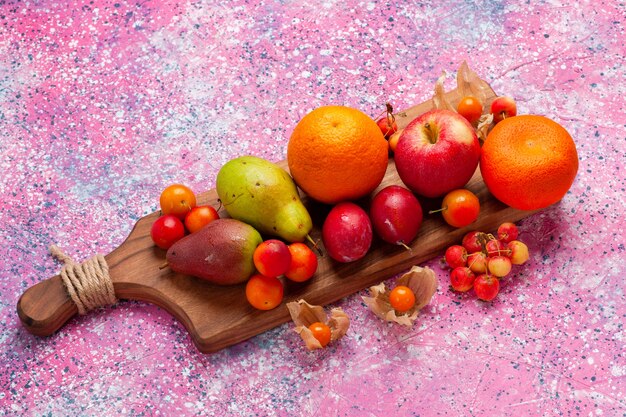 Top view different fruit composition fresh and mellow fruits on pink background.