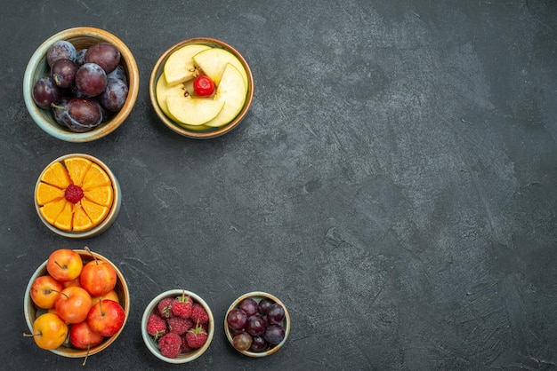 Top view different fruits composition fresh fruits inside pots on dark background health fresh ripe fruits mellow