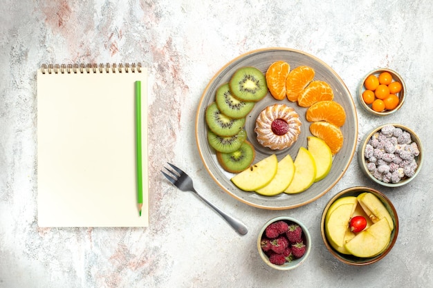 Вид сверху разные фруктовые композиции, свежие фрукты с маленьким пирогом на белом фоне, спелые фрукты, витамин, здоровье, спелые