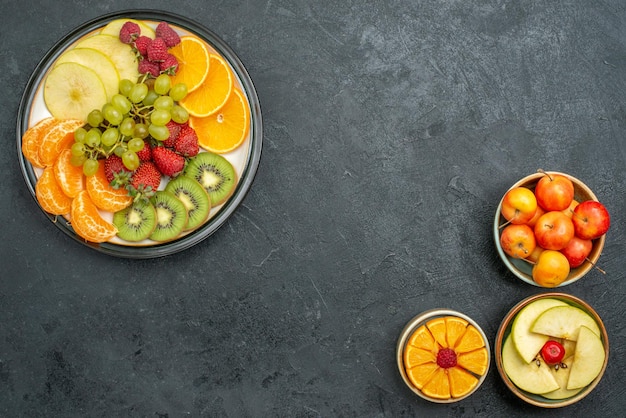 Vista dall'alto composizione di diversi frutti frutta fresca e affettata su sfondo scuro frutta fresca dieta matura per la salute