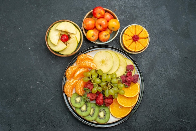 Top view different fruits composition fresh mellow and sliced fruits on a dark background fresh fruits mellow health ripe