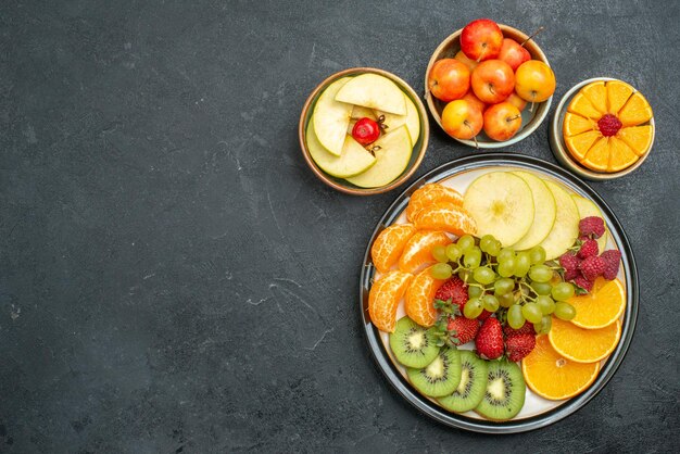 Top view different fruits composition fresh and sliced fruits on a dark background fresh fruits mellow health ripe