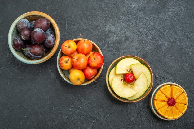 Top view different fruits composition fresh and sliced fruits on dark background fresh fruits mellow health ripe