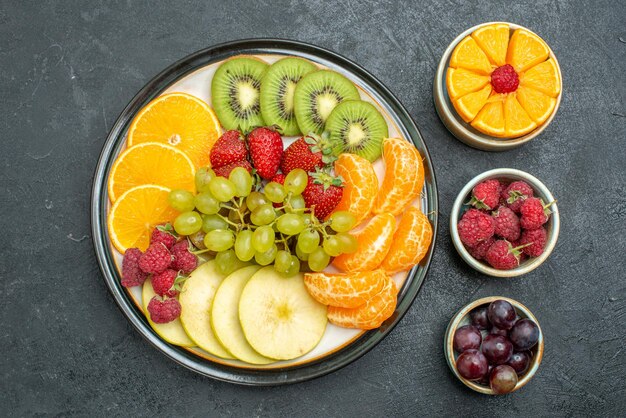 Top view different fruits composition fresh and sliced fruits on dark background health fresh fruit mellow ripe