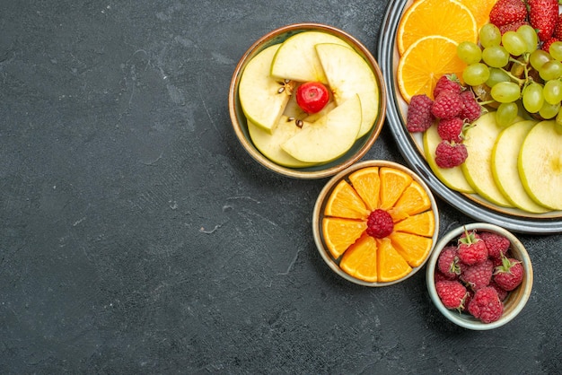 Top view different fruits composition fresh and sliced fruits on dark background health ripe fresh fruit mellow