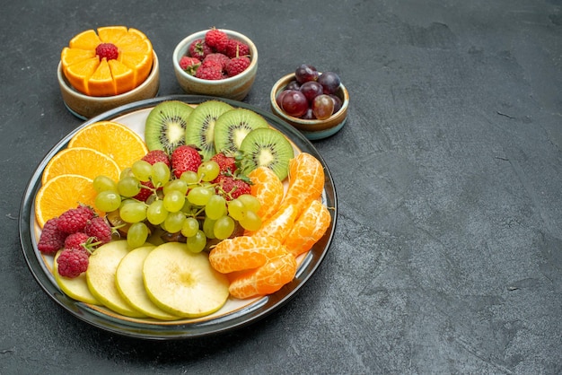 Top view different fruits composition fresh and sliced fruits on the dark background health ripe fresh fruit mellow