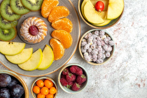 Top view different fruits composition fresh and sliced fruits on the white background vitamine mellow fruits health ripe