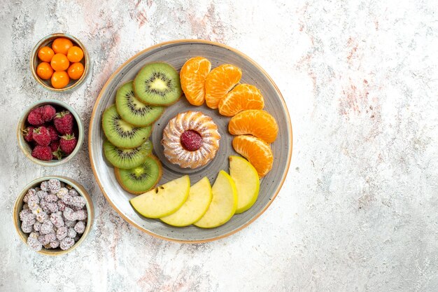 Вид сверху разных фруктов, свежие и нарезанные фрукты с тортом на белом фоне, спелые фрукты, здоровье, спелые витамины