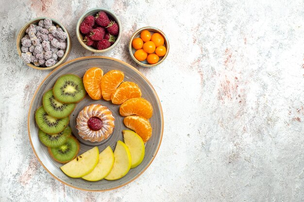 Top view different fruits composition fresh and sliced fruits with cake on white background mellow fruits ripe vitamine health