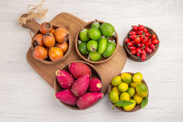 Бесплатное фото Вид сверху разных фруктов фейхоа, ягод и других фруктов внутри тарелок на белом фоне спелых продуктов экзотического цвета