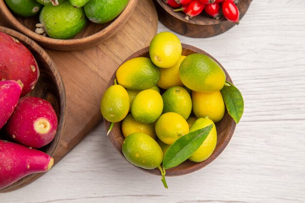 Top view different fruits feijoas berries and other fruits inside plates on white background ripe exotic  color