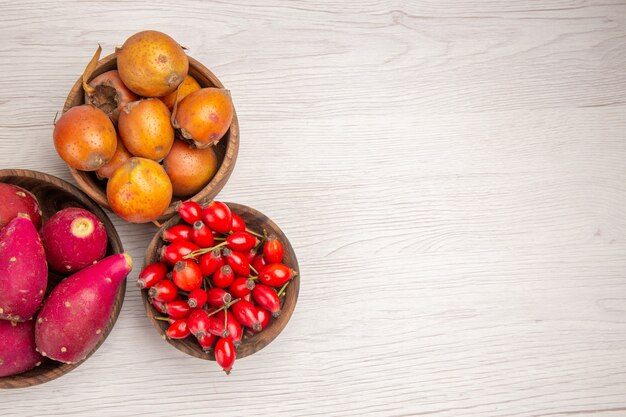 Top view different fruits feijoas and other fruits inside plates on white background health ripe exotic color tropical tree berry free place