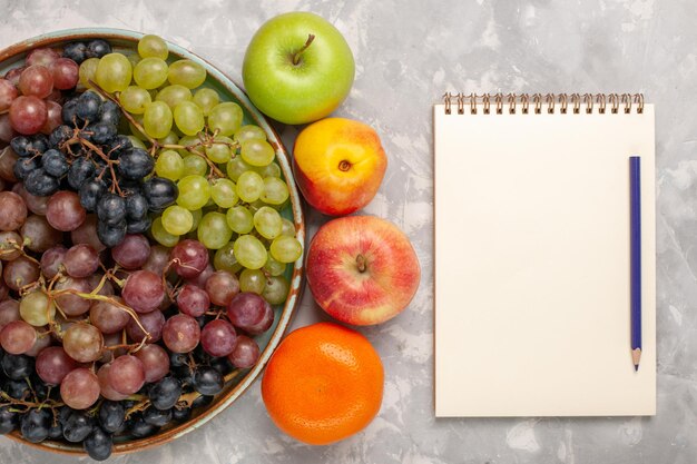 Foto gratuita vista dall'alto diverse uve con altri frutti sulla scrivania bianca chiara
