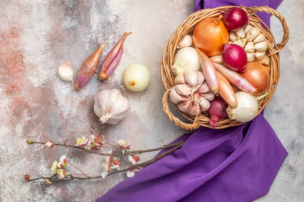 Top view different ingredients onions and garlic inside basket with purple tissue