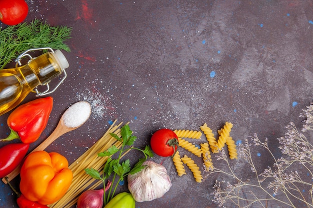 Vista dall'alto diversi ingredienti pasta cruda e verdure fresche sullo sfondo scuro prodotto alimentare salute insalata dieta