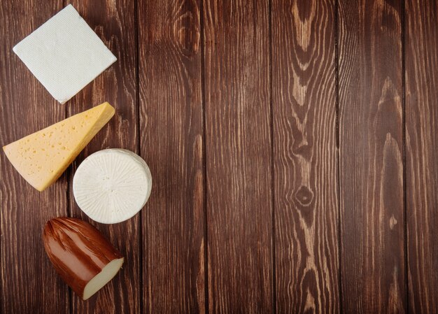 Top view of different kind of cheese on rustic wooden table with copy space