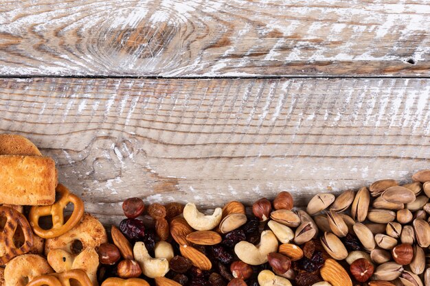 Top view of different kind of snacks as nuts, crackers and cookies with copy space on white wooden background horizontal