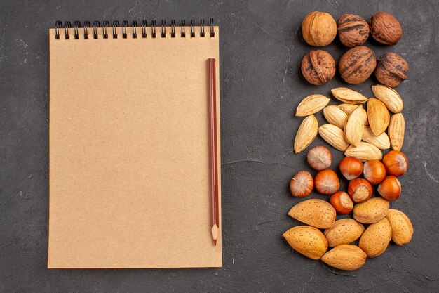 灰色の表面にメモ帳が付いているさまざまなナッツの新鮮なナッツの上面図