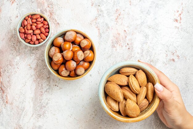 Top view different nuts inside little pots on white background nuts snack fresh walnut hazelnut peanut