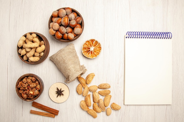 Top view different nuts inside little pots on a white desk nut snack walnut hazelnut