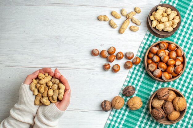 Top view different nuts peanuts hazelnuts and walnuts on white table in hand