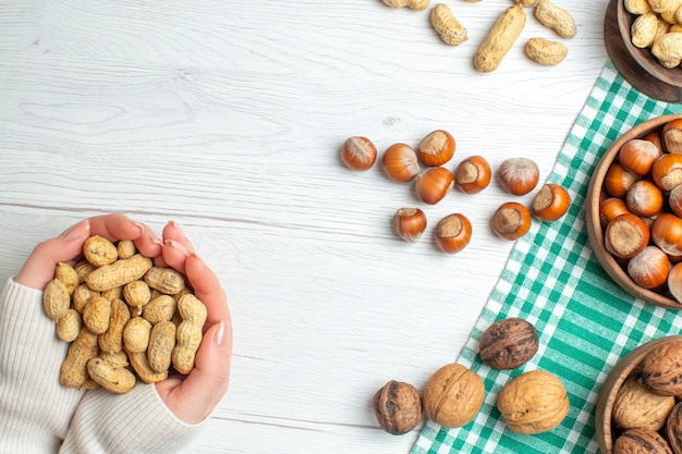 Top view different nuts peanuts hazelnuts and walnuts on white table