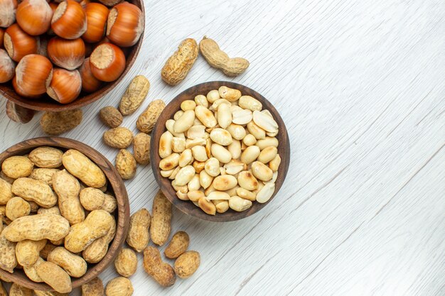 Top view different nuts peanuts hazelnuts and walnuts on white table