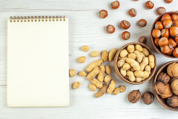 Top view different nuts peanuts hazelnuts and walnuts on white table