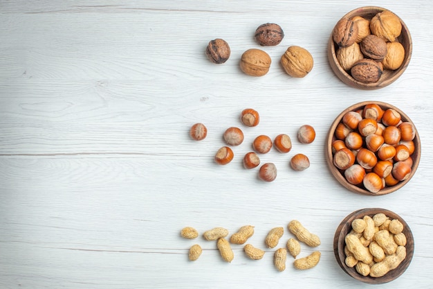 Top view different nuts peanuts hazelnuts and walnuts on white table