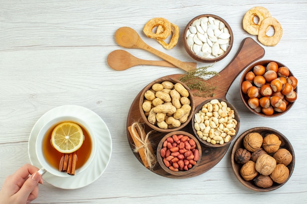 Top view different nuts peanuts hazelnuts and walnuts with cup of tea on white table