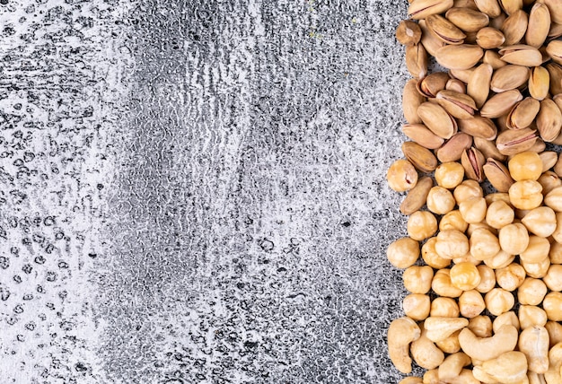 Top view different nuts with almonds and hazelnuts on dark stone table