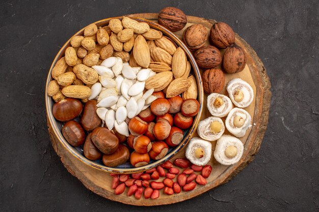 Top view of different nuts with confitures on dark surface