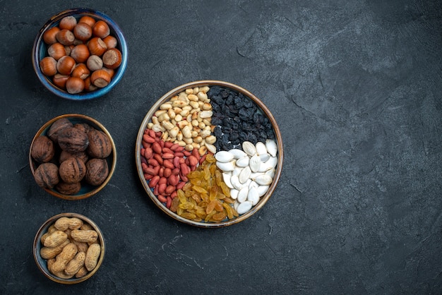 Top view different nuts with raisins and dried fruits on dark-grey background nuts snack hazelnut walnut peanuts