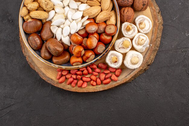 Top view of different nuts with white confitures on dark surface