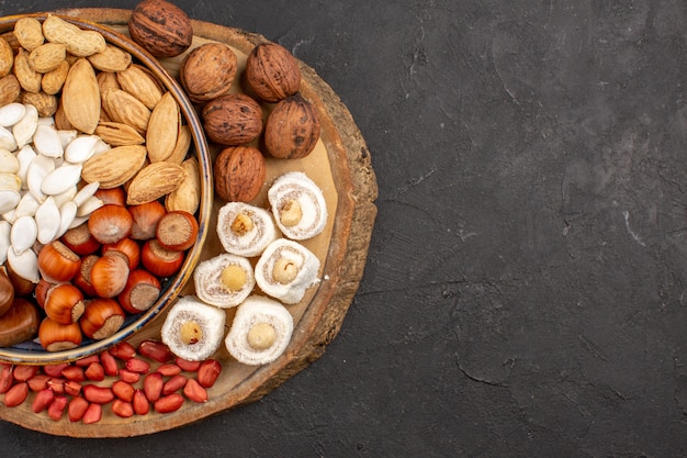 Top view of different nuts with white confitures on dark surface