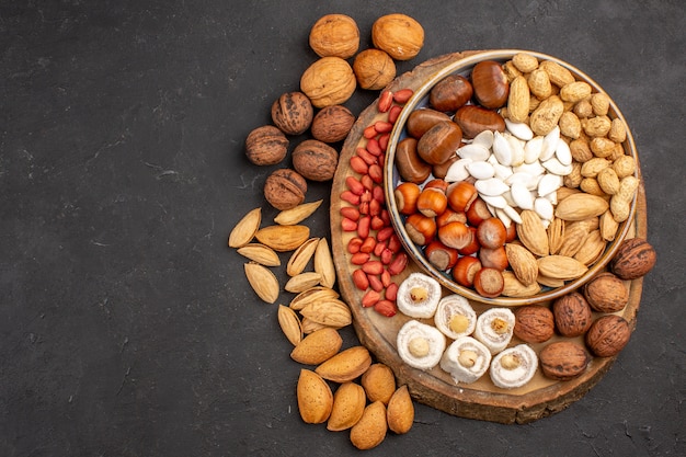 Top view of different nuts with white confitures on grey surface