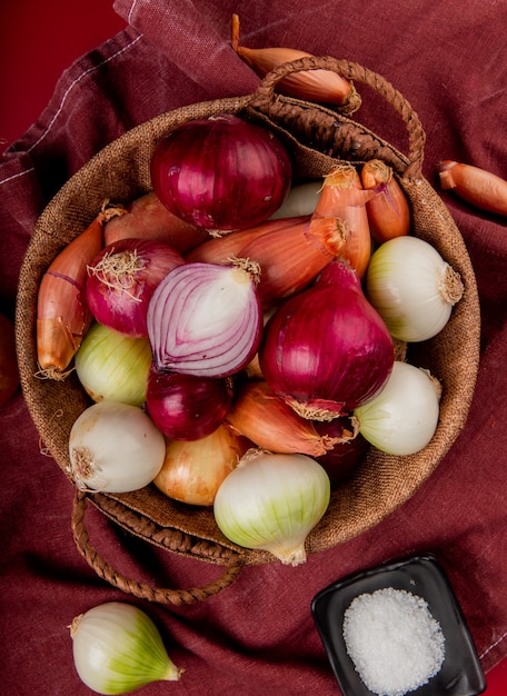 Free photo top view of different onions in basket with salt on bordo cloth and red