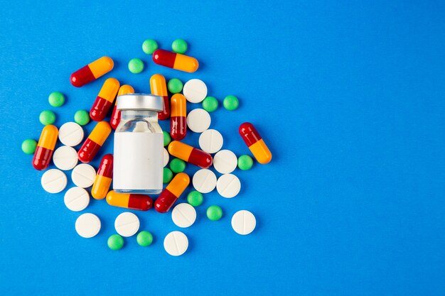 top view different pills with vaccine on blue background