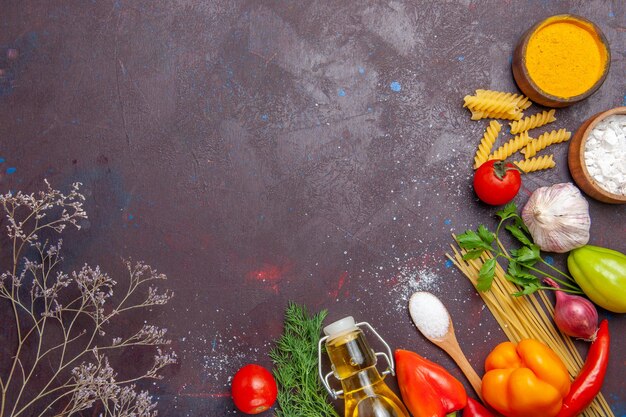 Top view different products raw pasta different seasonings and vegetables on dark background health diet raw food