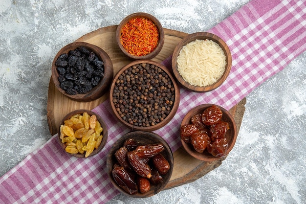 Top view different raisins with khurma and rice on white space