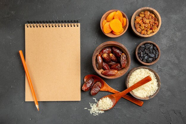 Top view different raisins with raw rice on a dark surface fruit dry raisin raw