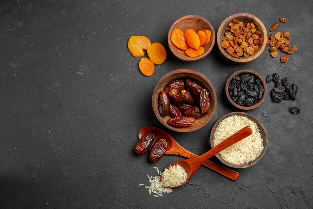 Top view different raisins with raw rice on the dark surface fruit dry raisin raw