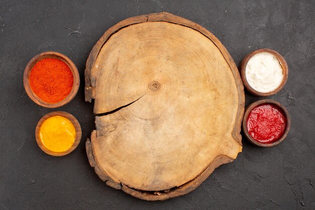 Top view of different seasonings inside little pots on black