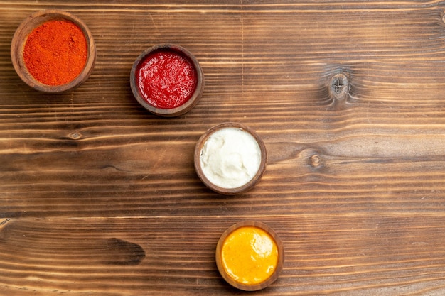 Top view of different seasonings inside little pots on brown wooden table